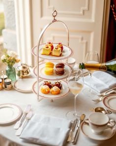 three tiered trays filled with pastries on top of a white table cloth