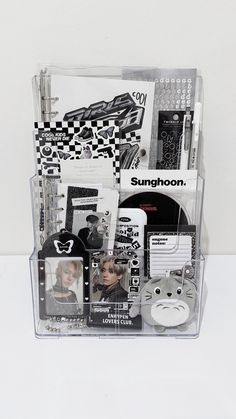 an assortment of items in a clear plastic container on a white surface with black and white images