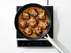 a skillet filled with meatballs and gravy on top of a stove