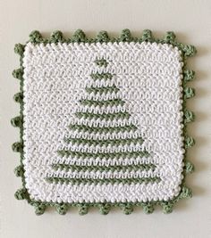 a crocheted christmas tree on a white wall with green trim around the edges