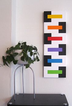 a potted plant sitting on top of a metal stand in front of a painting