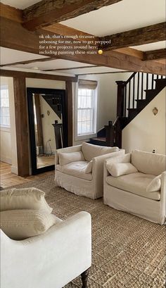 a living room with couches and chairs in front of a staircase that leads up to the second floor