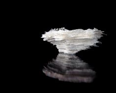 an iceberg floating in the water with its reflection on it's black surface