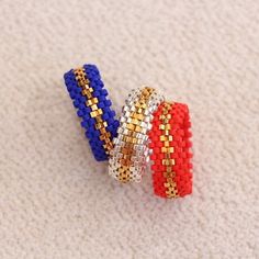 three beaded bracelets sitting on top of a white carpeted floor next to each other