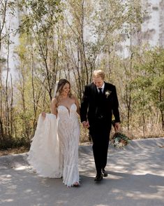 the bride and groom are walking down the path together in their wedding attire, holding hands