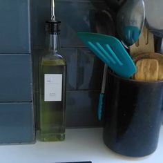 utensils and spoons are in a cup on the counter next to a bottle