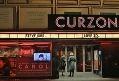 a movie theater with the name curzon on it's front and side windows lit up at night