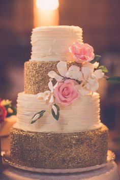 a three tiered wedding cake with gold glitter and pink flowers on the top layer