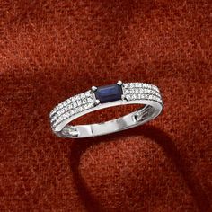 a diamond and sapphire ring on a red velvet surface