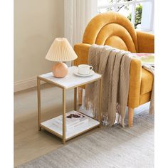 a small table with a lamp on it next to a yellow chair and a book