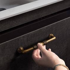 a person's hand reaching for a door handle on a drawer