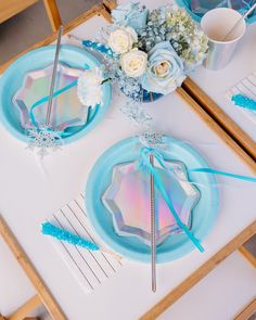 the table is set with blue and white plates, silverware, and flower centerpieces