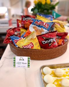 a basket filled with lots of candy sitting on top of a counter next to a bowl of chips