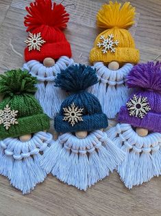 four knitted hats with tassels and snowflakes on them sitting on a wooden surface