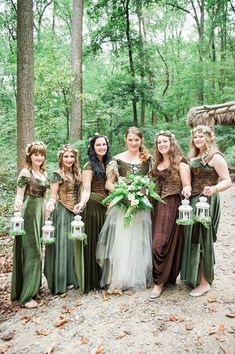 a group of women standing next to each other in front of trees and leaves holding lanterns