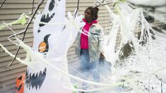 a woman standing in front of a house covered in ice and icing with halloween decorations on it