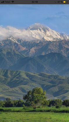 the mountain range is covered in snow and green grass, as seen from across the valley