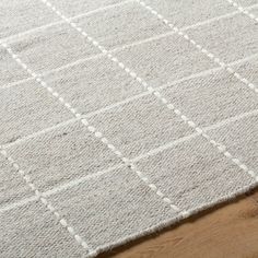 a close up of a rug on a wooden floor with white squares and lines in the middle