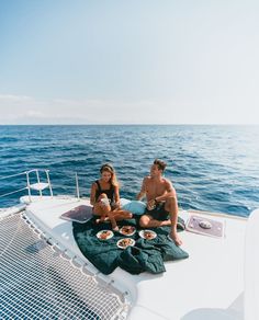 two people sitting on the back of a boat eating