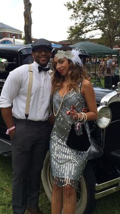 a man standing next to a woman in front of an old car at a car show