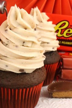 two chocolate cupcakes with white frosting and reese's candy bar in the background