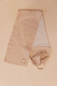 a tan and white polka dot scarf laying on top of a beige surface with a gold ring