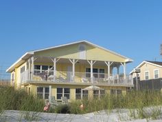 a yellow house on the beach with two balconies