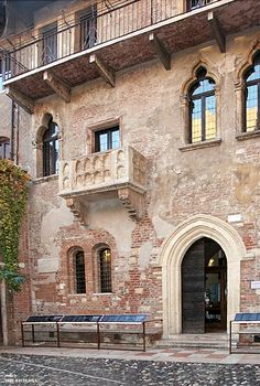 an old building with benches in front of it and windows on the side of the building