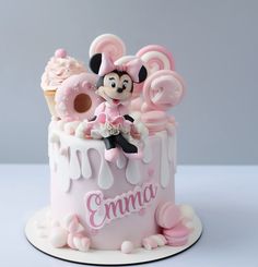 a minnie mouse cake with pink icing and decorations on it's top is shown