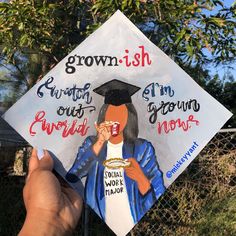 a hand holding up a graduation cap with the words grown ish written on it