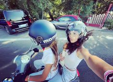 two girls on a motor scooter in the street