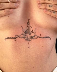 a woman's chest with an octopus tattoo on her left side and two hands holding it