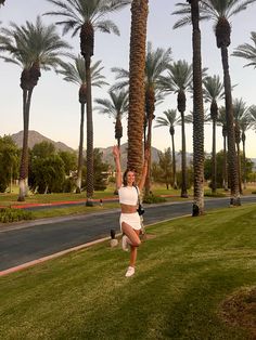 a woman standing in the grass near palm trees