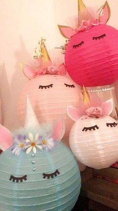 three paper lanterns with unicorn faces and flowers on them, one is pink the other is blue