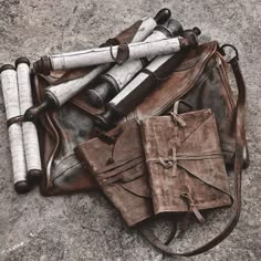 an old leather bag with rolled up papers and other items on it sitting on the ground