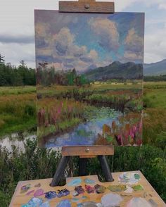 an easel with a painting on it sitting in front of a field