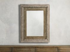 a mirror hanging on the wall above a wooden bench in front of a white wall