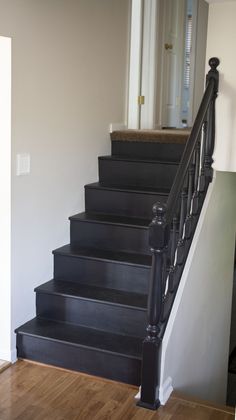 a set of black stairs leading up to a white door in a room with hardwood floors