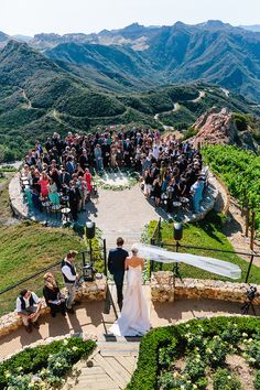 the bride and groom are walking down the stairs to their wedding ceremony at the top of the mountain