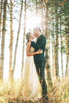 a bride and groom are standing in the woods with their arms around each other as they kiss