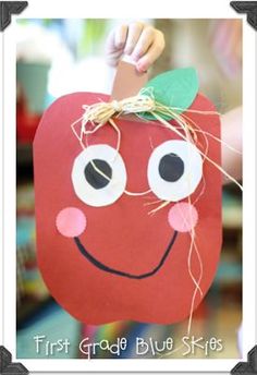 a paper apple with eyes and a bow on it's head is hanging from a string