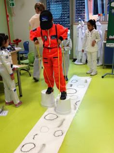 a man in an orange jumpsuit standing on top of white buckets and measuring tape