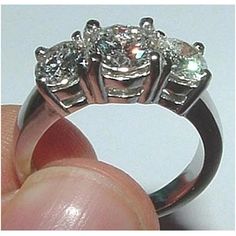 a hand holding a three stone diamond ring