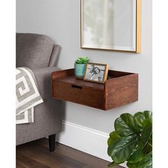 a small wooden shelf with a plant on it next to a mirror and couch in a living room