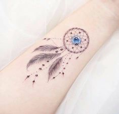 a woman's arm with a tattoo on it that has a small dream catcher