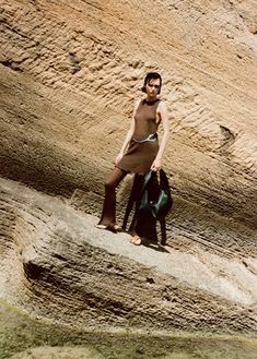 a man standing on the side of a cliff next to a body of water with a bag in his hand