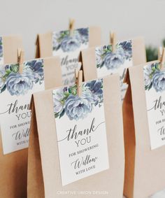 small bags with flowers on them are sitting on a table, one has a thank you tag attached to it