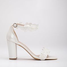 a woman's white high heeled sandal with flower decoration on the ankle