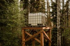 a wooden structure in the middle of a forest filled with trees and tall pine trees