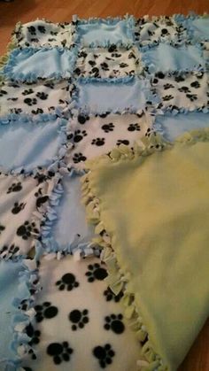 a dog themed blanket on the floor with black and white paw prints in blue, green, and yellow